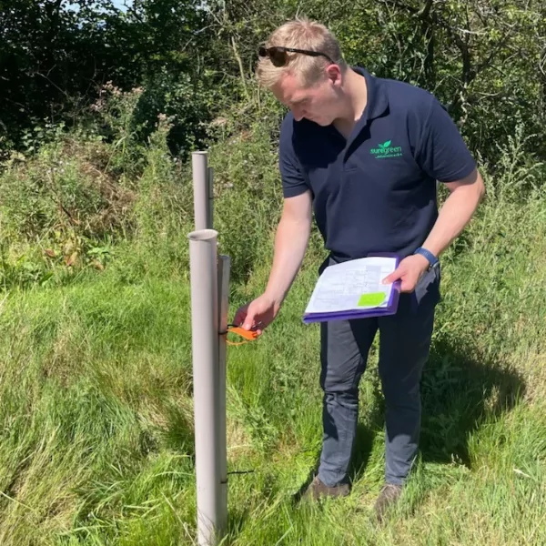 A man inspecting a biodegradable tree shelter